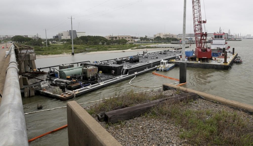 Spill booms surround a barge at the Pelican Island bridge in Galveston, Texas, Wednesday, May 16, 2024. The barge collided with the bridge Tuesday which caused a partial collapse of the bridge and spilled vacuum gas oil the barge was carrying into Galveston Bay. (Jennifer Reynolds/The Galveston County Daily News via AP)