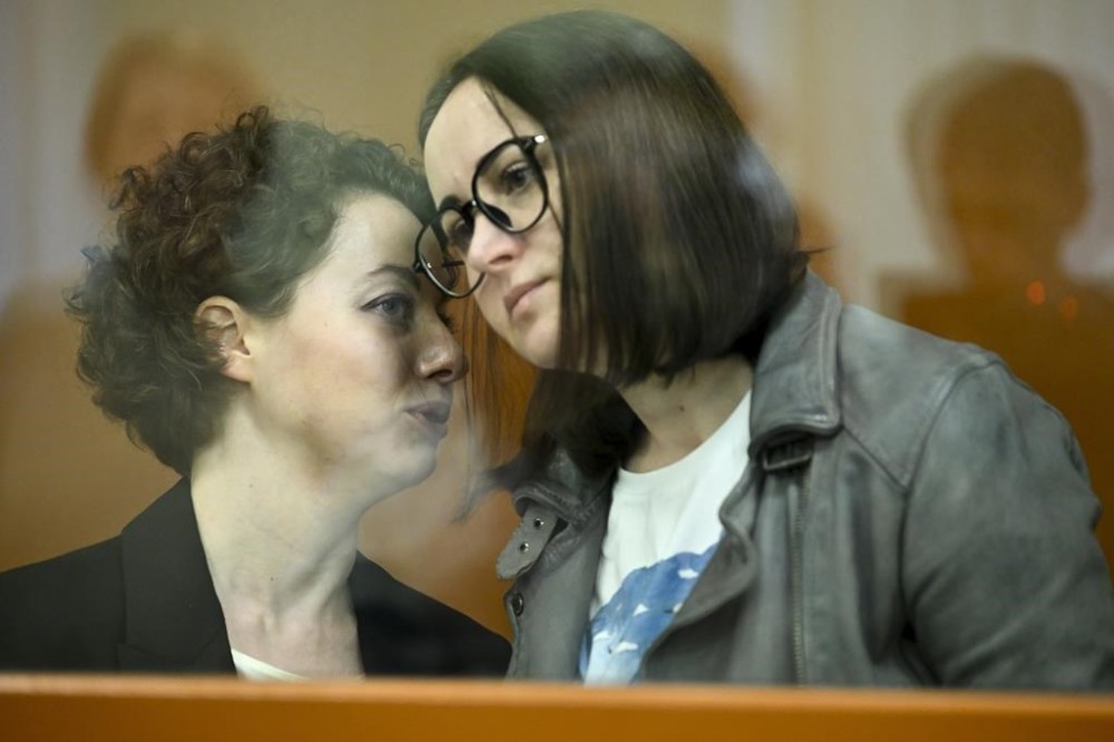 Theater director Zhenya Berkovich, left, and playwright Svetlana Petriychuk are seen in a glass cage prior to a hearing in a court in Moscow, Russia, Monday, May 20, 2024. Berkovich, a prominent independent theater director, and Petriychuk, a playwright have been behind bars since early May. Authorities claim a play they staged,