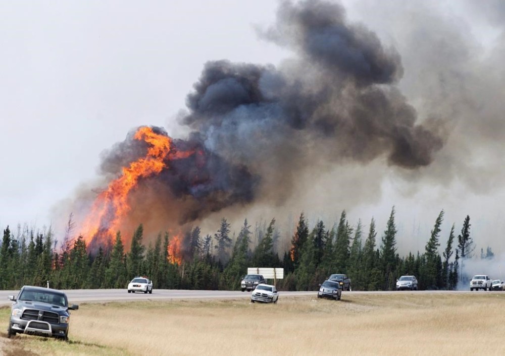 RCMP escort evacuees from Fort McMurray, Alberta past wildfires that were still burning out of control Saturday, May 7, 2016. THE CANADIAN PRESS/Ryan Remiorz