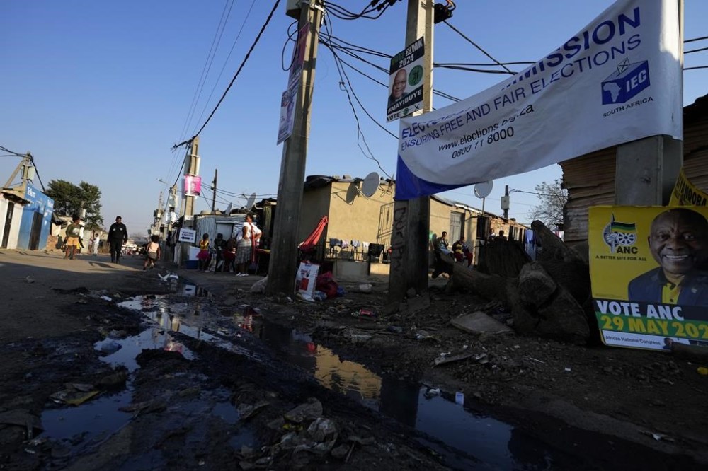 A polling station sign and political posters are displayed outside a voting station in Alexandra, north of Johannesburg, South Africa, Tuesday, May 28, 2024, ahead of the elections on Wednesday May 29. (AP Photo/Themba Hadebe)