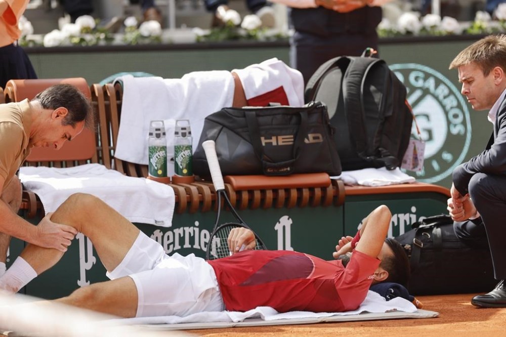 Serbia's Novak Djokovic receives medical assistance for his right knee during his fourth round match of the French Open tennis tournament against Argentina's Francisco Cerundolo at the Roland Garros stadium in Paris, Monday, June 3, 2024. (AP Photo/Jean-Francois Badias)