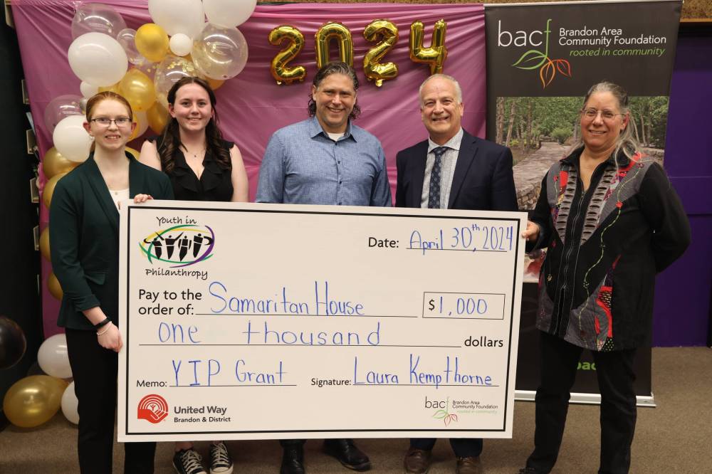 Youth in Philanthropy at Vincent Massey High School president Abby Wruth (from left), vice-president Allison McQuigge, Brandon Mayor Jeff Fawcett, Brandon School Division Supt. Mathew Gustafson and Samaritan House Ministries food bank co-ordinator Marcia Hamm-Wiebe pose for a photo at the grant presentation on Tuesday. (Abiola Odutola/The Brandon Sun)