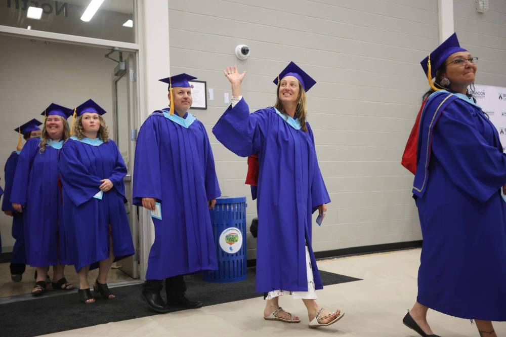 A graduate waves to supporters in the crowd while entering Brandon University’s convocation for the Faculty of Education on Thursday afternoon. (Tim Smith/The Brandon Sun)