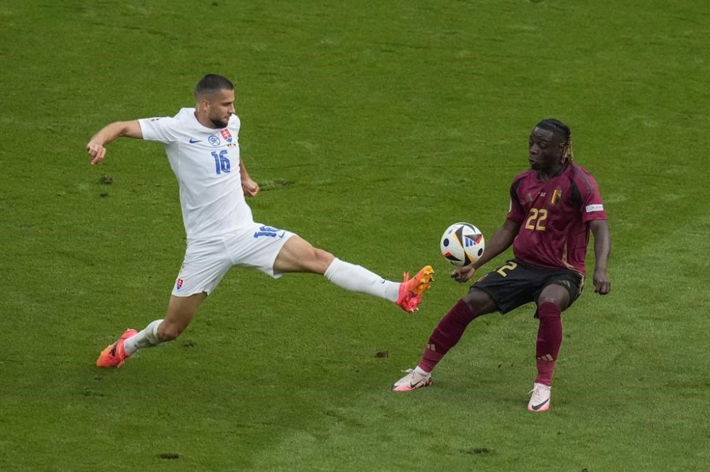Slovakia's David Hancko, left, lunges for the ball against Belgium's Jeremy Doku during the Group E match between Belgium and Slovakia at the Euro 2024 soccer tournament in Frankfurt, Germany, Monday, June 17, 2024. (AP Photo/Themba Hadebe)