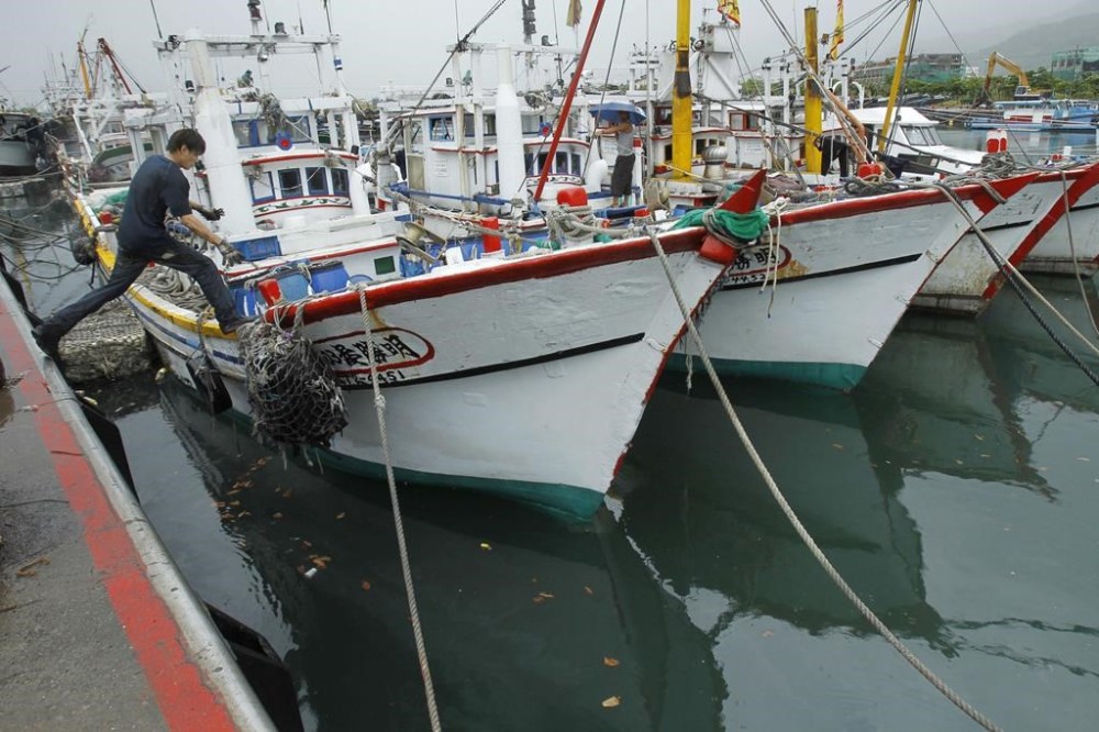 FILE - A fisherman leaps to his boat docked in harbor in Toucheng, north eastern Taiwan, Aug. 21, 2013. Taiwan said the Chinese coast guard boarded a Taiwanese fishing boat Tuesday, July 2, 2024, before steering it to a port in mainland China, and demanded that Beijing release the vessel. (AP Photo/Wally Santana, File)