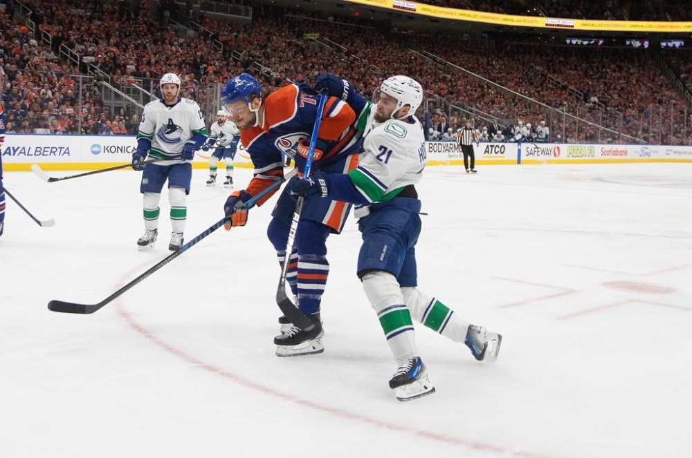 Vancouver Canucks' Nils Hoglander (21) is checked by Edmonton Oilers' Vincent Desharnais (73) during NHL playoff action in Edmonton on Saturday May 18, 2024. THE CANADIAN PRESS/Jason Franson