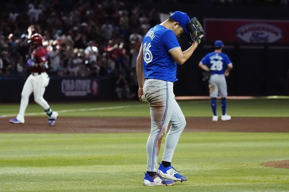 Toronto Blue Jays starting pitcher Yusei Kikuchi, center, reacts after giving up a grand slam against Arizona Diamondbacks' Ketel Marte, left, as Blue Jays third baseman Ernie Clement (28) watches the home run during the fifth inning of a baseball game, Sunday, July 14, 2024, in Phoenix. (AP Photo/Ross D. Franklin)