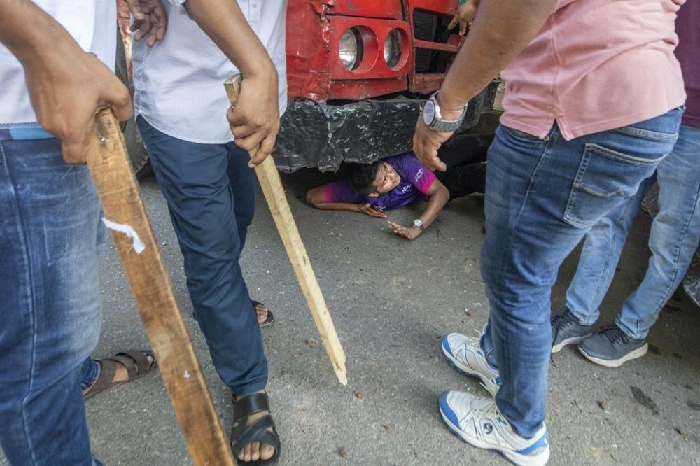 A student hides beneath a vechicle as students clash over quota system at Jahangir Nagar University at Savar outside Dhaka, Bangladesh, Monday, July 15, 2024. Police have fired tear gas and charged with batons overnight during violent clashes between a pro-government student body and student protesters, leaving dozens injured at a leading public university outside Bangladesh's capital over quota system in government jobs, police and students said Tuesday.(AP Photo/Abdul Goni)