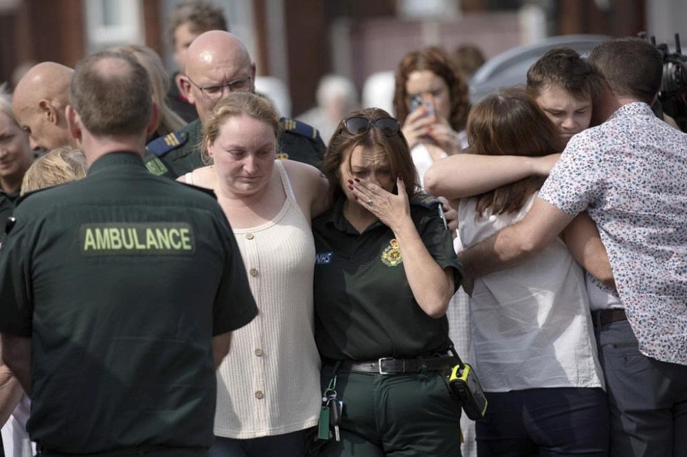 Emergency personnel comfort members of the public near the scene in Hart Street, where three children died and eight were injured in a knife attack during a Taylor Swift event at a dance school on Monday, in Southport, England, Tuesday, July 30, 2024. (James Speakman/PA via AP)