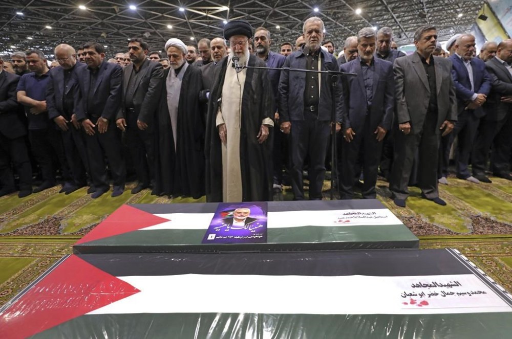 In this photo released by an official website of the office of the Iranian supreme leader, Supreme Leader Ayatollah Ali Khamenei, center, leads a prayer over the coffins of Hamas leader Ismail Haniyeh and his bodyguard who were killed in an assassination blamed on Israel on Wednesday, during their funeral ceremony at the Tehran University campus, in Tehran, Iran, Thursday, Aug. 1, 2024. Iranian President Masoud Pezeshkian prays at center right. (Office of the Iranian Supreme Leader via AP)