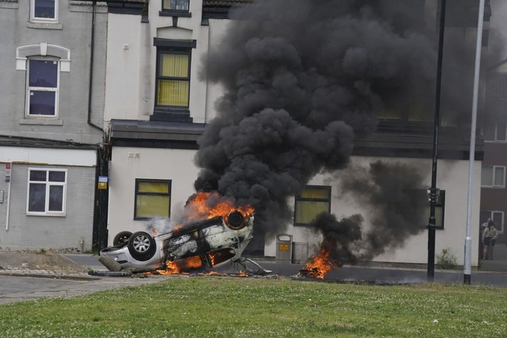 A car burns after being overturned during an anti-immigration protest in Middlesbrough, England, Sunday Aug. 4, 2024. (Owen Humphreys/PA via AP)