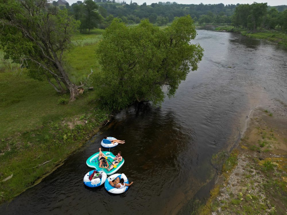 A precariously rooted tree on the riverbank provides a little bit of shade for the floaters. (Tim Smith/The Brandon Sun)