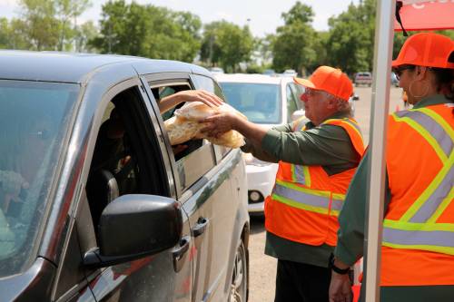 Cars line up at the Keystone Centre's east parking lot as drivers grab bags of hash browns and french fries being handed out by volunteers during a previous Free Fry Day fundraiser in Brandon. (The Brandon Sun files)