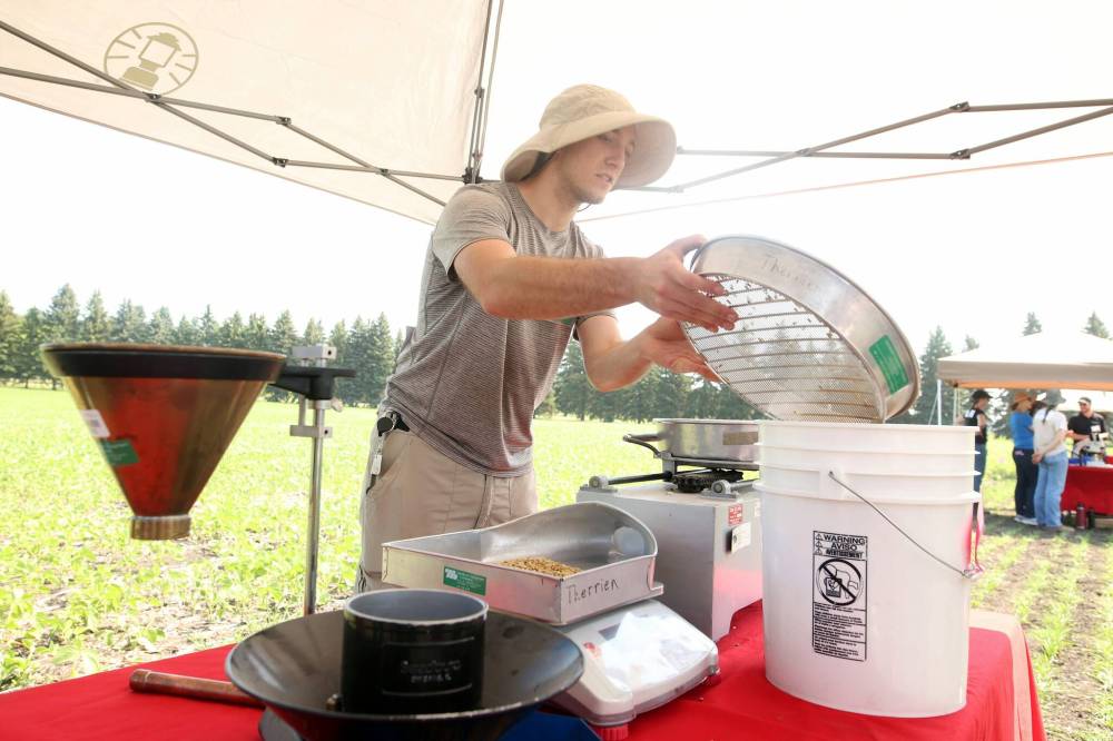 Summer student Jack Claussen shows visitors how the assortment and sizing shaker works during the centre’s centennial celebration on Thursday.