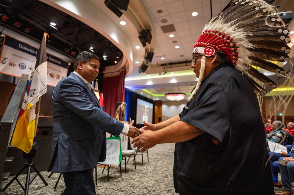 Gary Anandasangaree, minister of Crown-Indigenous relations (left), shakes hands with Canupawakpa Dakota Nation Chief Raymond Brown during a ceremony where the Canadian government delivered a formal apology to the nine Dakota and Lakota First Nations in Canada in Whitecap Dakota Nation, Sask., on Monday. (The Canadian Press)