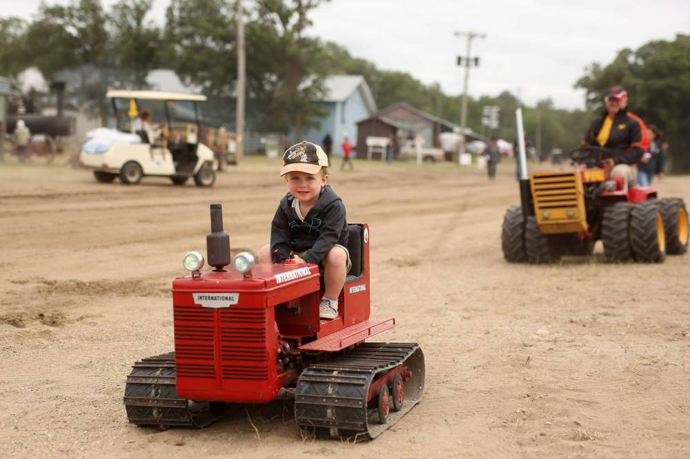 Brooks Combot of St. Eustache rides a miniature tractor while making his way to take part in the Pioneer Power Parade at last year’s Manitoba Threshermen’s Reunion and Stampede near Austin. This year’s Threshermen’s Reunion starts today. (File)