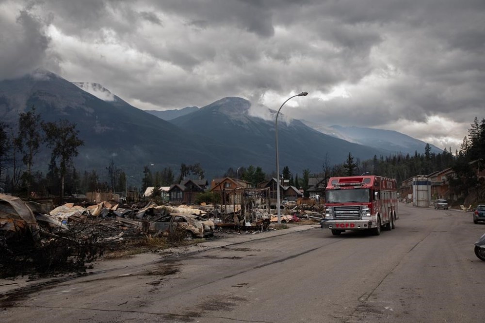 A fire truck travels past a devastated residential block in Jasper, Alta., on Friday July 26, 2024. Jasper residents who lost their homes in last month’s wildfire face unique rebuilding challenges tied to leasing provisions nearly as old as Canada. THE CANADIAN PRESS/Amber Bracken