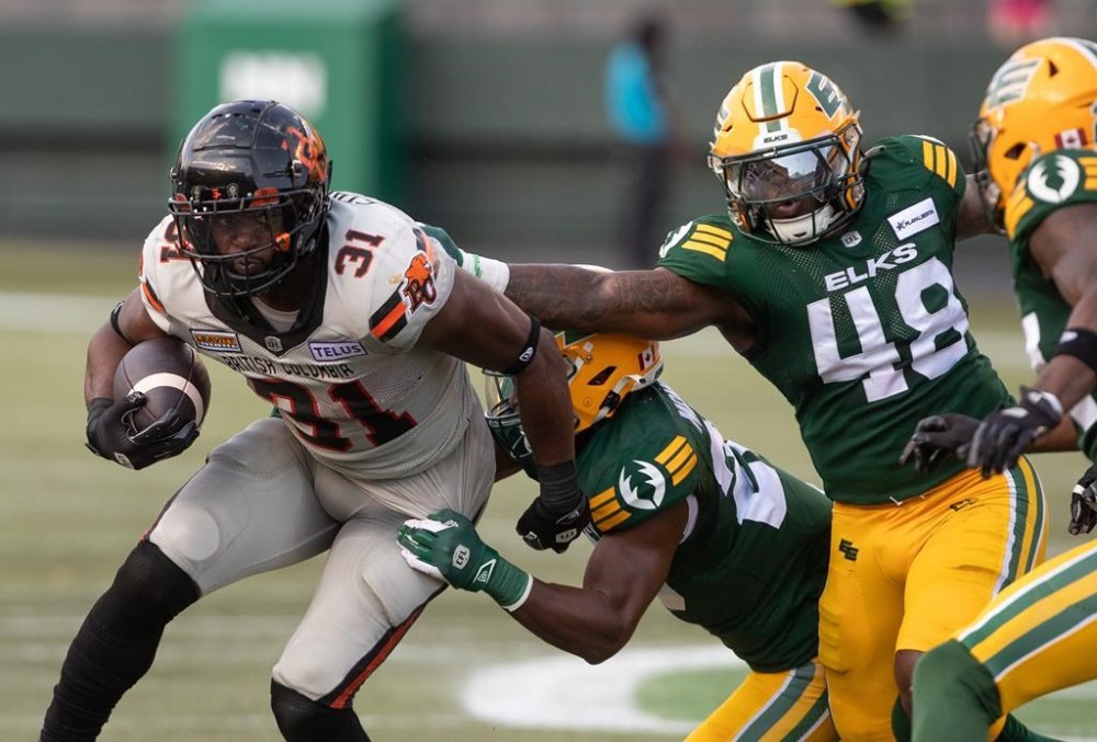 B.C. Lions ' William Stanback (31) is grabbed by Edmonton Elks' Derrick Moncrief (29) and Nick Anderson (48) during first half CFL action in Edmonton, Sunday, Aug. 11, 2024. THE CANADIAN PRESS/Jason Franson.