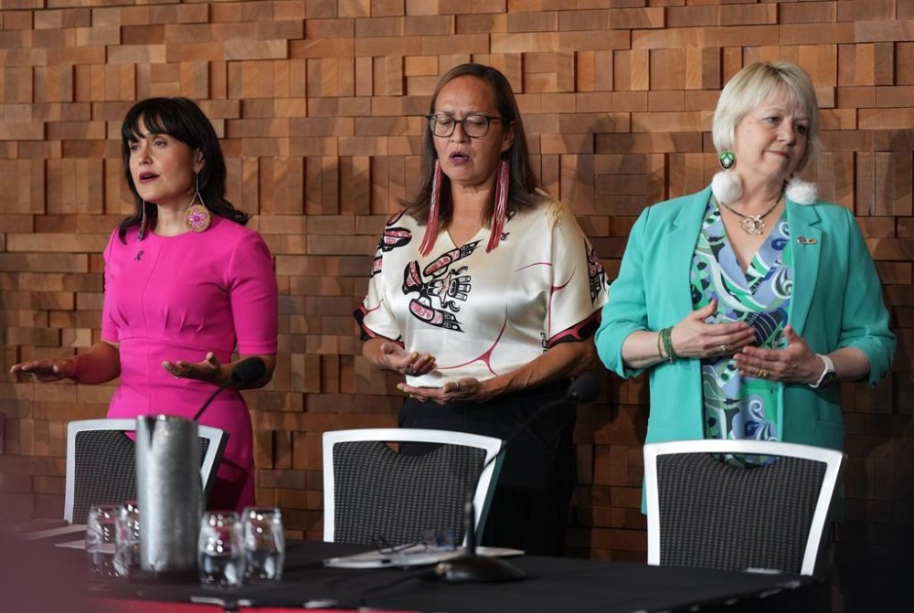 From left, B.C. Deputy Provincial Health Officer for Indigenous Health Dr. Daniele Behn Smith, First Nations Health Authority Chief Medical Officer Dr. Cornelia Wieman and B.C. Provincial Health Officer Dr. Bonnie Henry stand during a song before a news conference, in Vancouver, on Wednesday, August 21, 2024. The First Nations Health Authority and the office of the provincial health officer released an interim update related to the First Nations Population Health and Wellness Agenda. THE CANADIAN PRESS/Darryl Dyck