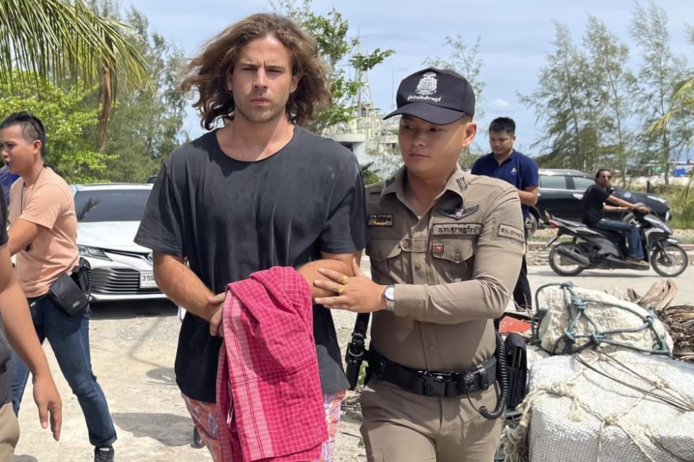 FILE - A Thai police officer escorts Spanish Daniel Sancho Bronchalo on suspicion of murdering and dismembering a Colombian surgeon from Koh Phagnan island to Koh Samui Island court, southern Thailand, Monday, Aug. 7, 2023. (AP Photo/Somkeat Ruksaman, File )