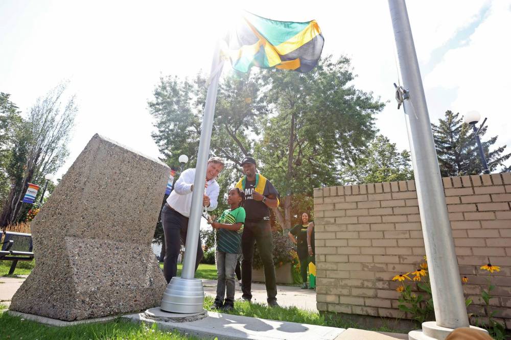 Brandon Mayor Jeff Fawcett and six-year-old Zurik Henlon raise the flag for Jamaica as Emelio Brown, president of the Westman Jamaican Community and secretary-treasurer for the Brandon Chamber of Commerce, looks on during a celebration of the independence day of Jamaica at Brandon City Hall on Tuesday. (Tim Smith/The Brandon Sun)