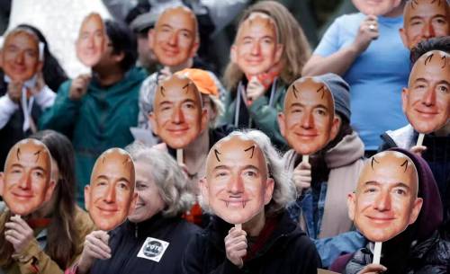 Demonstrators against Amazon's facial recognition software hold images of Amazon founder and former CEO Jeff Bezos near their faces at Amazon headquarters. (The Associated Press files)