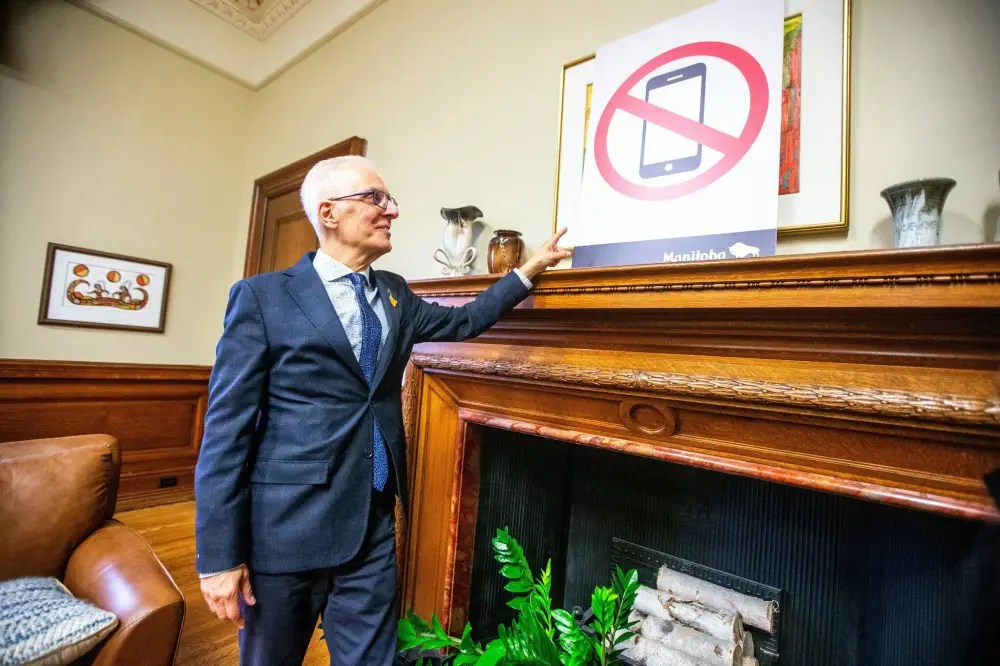 Education minister Nello Altomare shows new school signage (related to the cell phone ban) in his office at the Manitoba Legislative Building. (File)