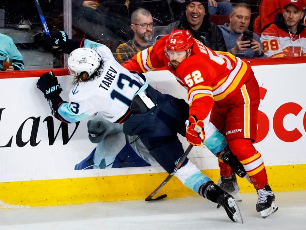 Calgary Flames defenceman MacKenzie Weegar (52) checks Seattle Kraken forward Brandon Tanev (13) during NHL hockey action in Calgary, Monday, March 4, 2024.THE CANADIAN PRESS/Jeff McIntosh