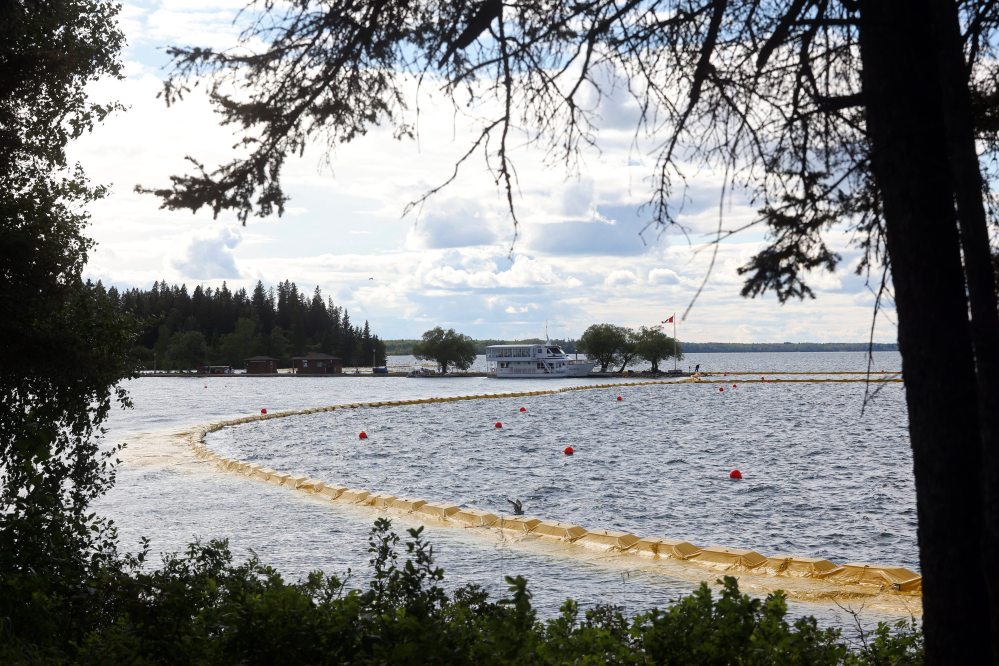 The containment curtain set up to prevent the spread of zebra mussels in Clear Lake in Riding Mountain National Park is seen last month along with the Martese cruise boat at the marina, which is currently docked for the season as part of ongoing zebra mussel mitigation. (File)