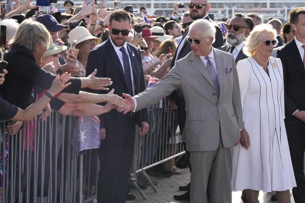 Britain's King Charles III, second from right, reaches out to greet the crowd as Queen Camilla stands beside him during their visit to the Sydney Opera House in Sydney, Australia, Tuesday, Oct. 22, 2024. (AP Photo/Mark Baker, Pool)