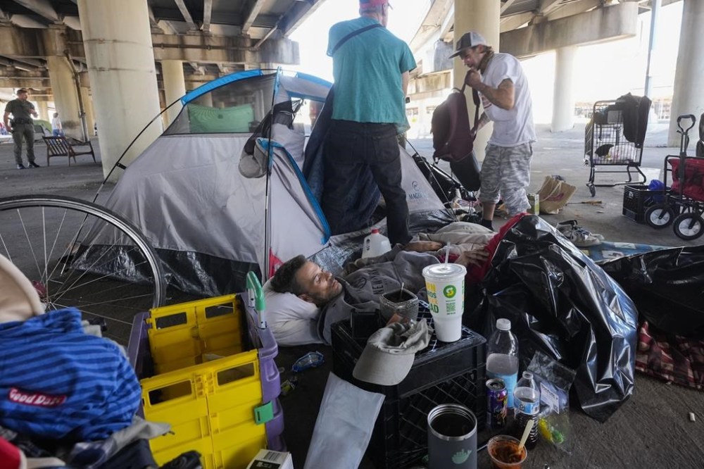 People living in a homeless encampment pick up belongings after Louisiana State police gave instructions for them to move to a different pre-designated location as they perform a sweep in advance of a Taylor Swift concert in New Orleans, Wednesday, Oct. 23, 2024. (AP Photo/Gerald Herbert)