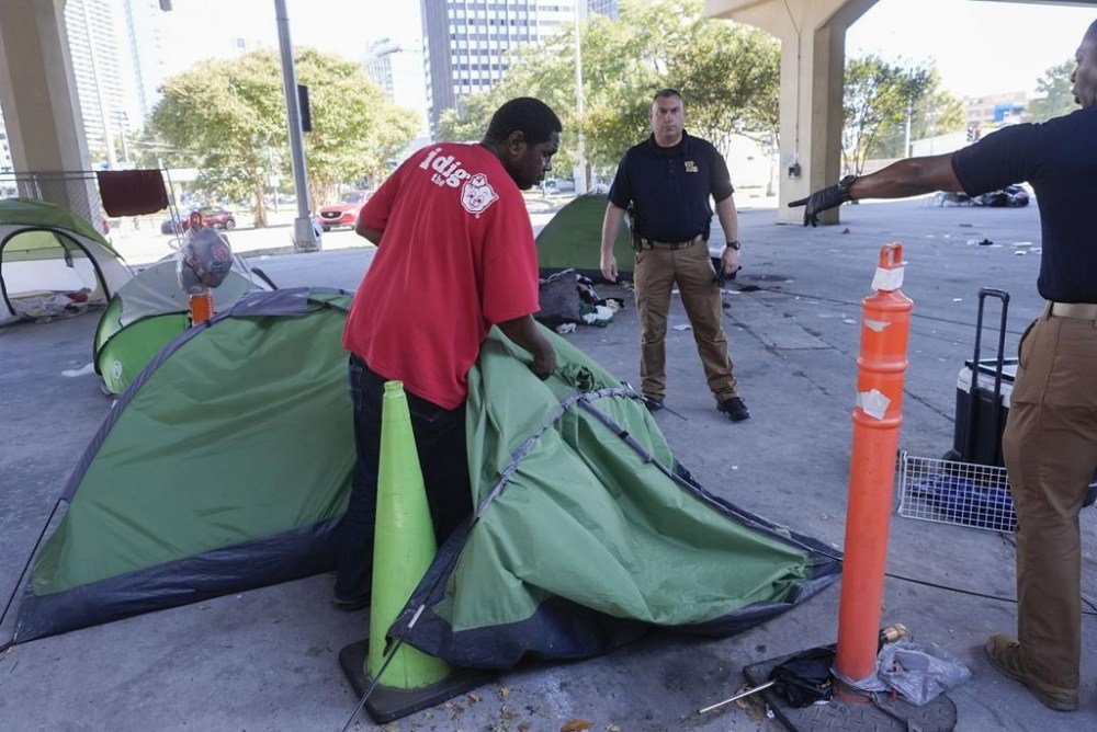 Louisiana State police give instructions to people living in a homeless encampment to move to a different pre-designated location as they perform a sweep in advance of a Taylor Swift concert in New Orleans, Wednesday, Oct. 23, 2024. (AP Photo/Gerald Herbert)