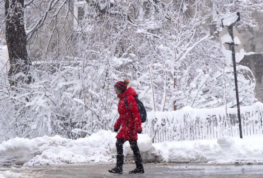 A pedestrian crosses the street through the snow as a spring storm dumped over 20cm of snow in Montreal on April 4, 2024. THE CANADIAN PRESS/Ryan Remiorz