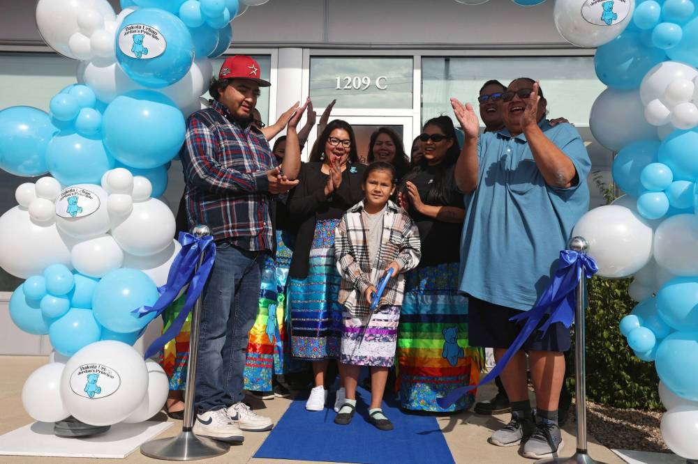Birdtail Sioux First Nation Chief Lindsay Bunn Jr., Dakota Urban case manager for Canupawakpa and former Sioux Valley Dakota Nation chief Jennifer Bone and Canupawakpa Dakota Nation Chief Raymond Brown surround seven-year-old Fawn Kasto of Birdtail Sioux First Nation, who lives in Brandon, along with other dignitaries as she cuts the ribbon during the grand opening of the Dakota Urban Jordan’s Principle office on Richmond Avenue in Brandon on Friday. (Tim Smith/The Brandon Sun)