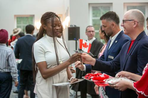 Oreo Amogu, 31, (left) receives a Canadian flag from Winnipeg Mayor Scott Gillingham during a Canada Day citizenship ceremony in Winnipeg in 2024. (Winnipeg Free Press files)