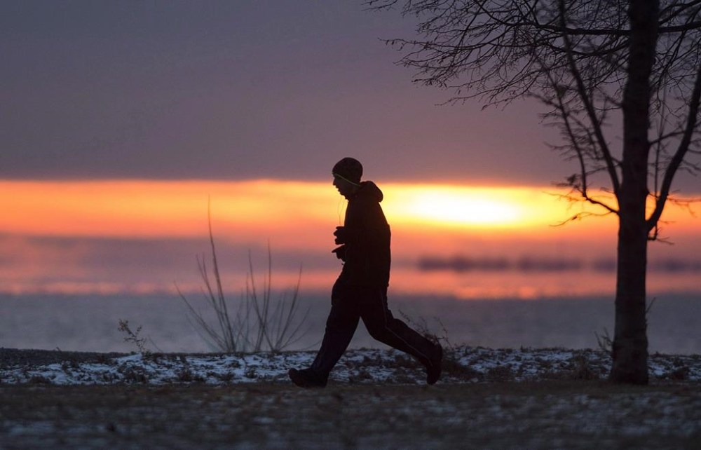 A man jogs along the banks of Lac-Saint-Louis as the sun sets in Montreal on December 27, 2018. THE CANADIAN PRESS/Graham Hughes