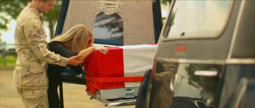 This image is the re-enactment of the repatriation of the body of Sapper Sean Greenfield. His sister Ainsley Christiensen grieves as the flag-draped transfer case is slid into the hearse for the drive down the Highway of Heroes to the coroner’s office in Toronto, Ont. (Submitted)