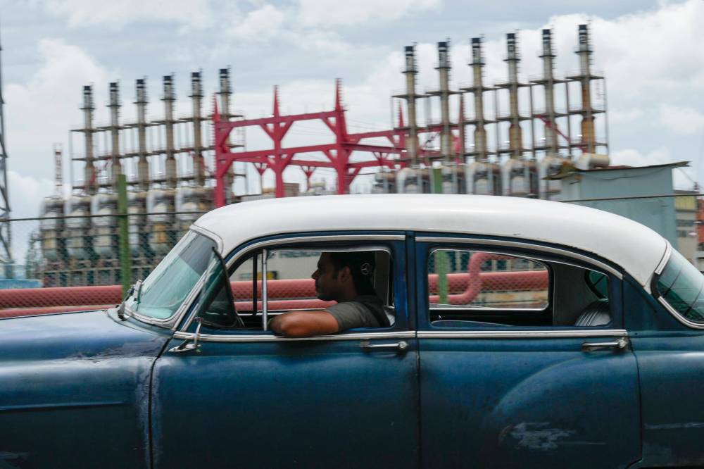 A person drives a classic American car past a floating generator that had not produced electricity for days in Havana, Cuba, last month. (The Associated Press)