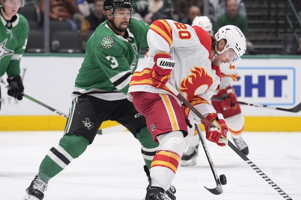 Calgary Flames center Blake Coleman (20) and Dallas Stars defenseman Mathew Dumba (3) skate for control of the puck during the second period of an NHL hockey game Sunday, Dec. 8, 2024, in Dallas. (AP Photo/LM Otero)