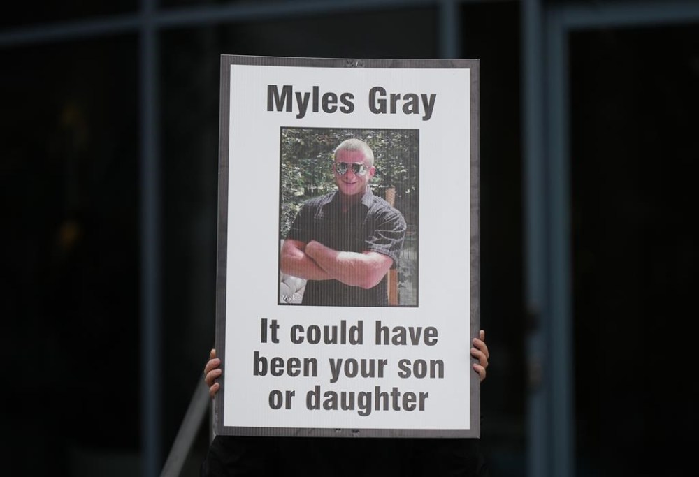 A person holds a sign with a photo of Myles Gray before the start of a coroner's inquest into his death, in Burnaby, B.C., on April 17, 2023. Gray died following a confrontation with several police officers in 2015. THE CANADIAN PRESS/Darryl Dyck