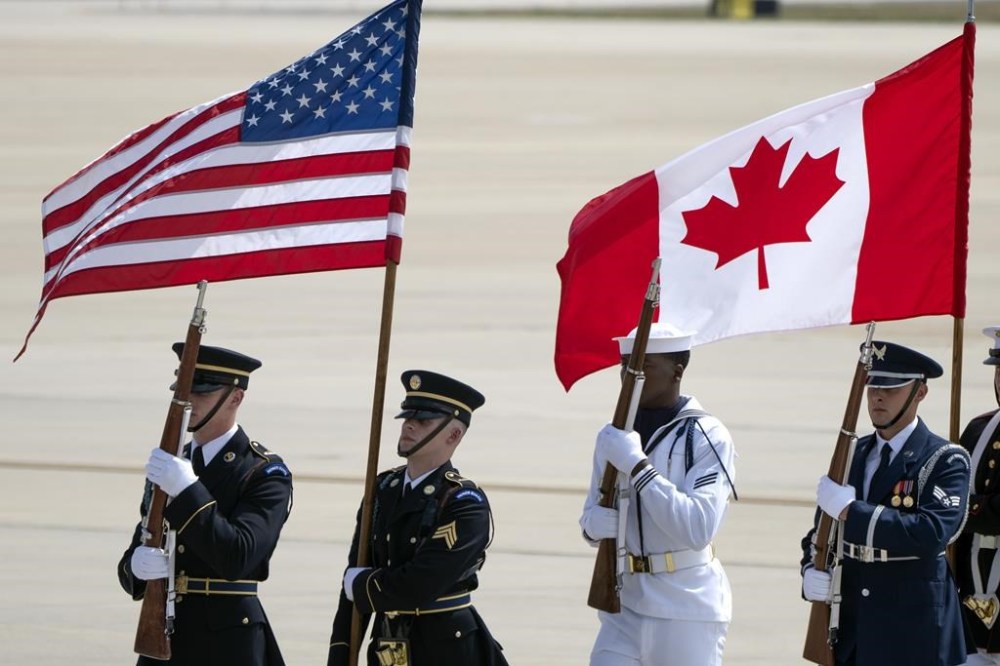 An honor guard marches in formation with U.S. and Canadian flags after the arrival of Canadian Prime Minister Justin Trudeau, at Andrews Air Force Base, Md., to attend the NATO summit in Washington, Monday, July 8, 2024. THE CANADIAN PRESS/AP-Mark Schiefelbein