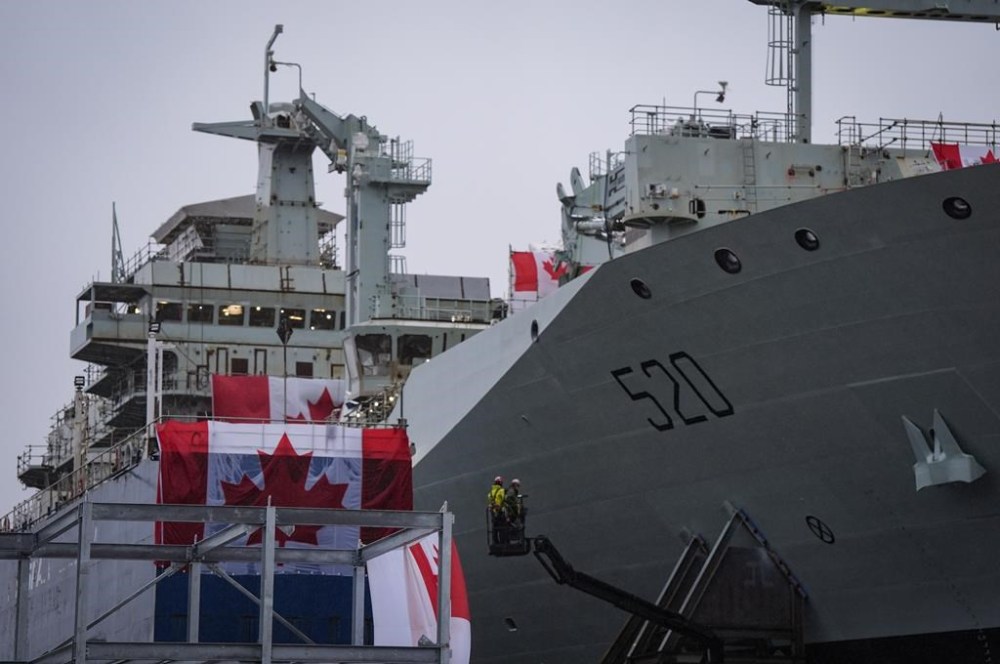 Workers are seen on a lift beside the new Royal Canadian Navy Joint Support vessel before a launch and naming ceremony at Seaspan Shipyards, in North Vancouver, B.C., on Friday, December 13, 2024. The ship is scheduled to be delivered to the Royal Canadian Navy in 2025. THE CANADIAN PRESS/Darryl Dyck