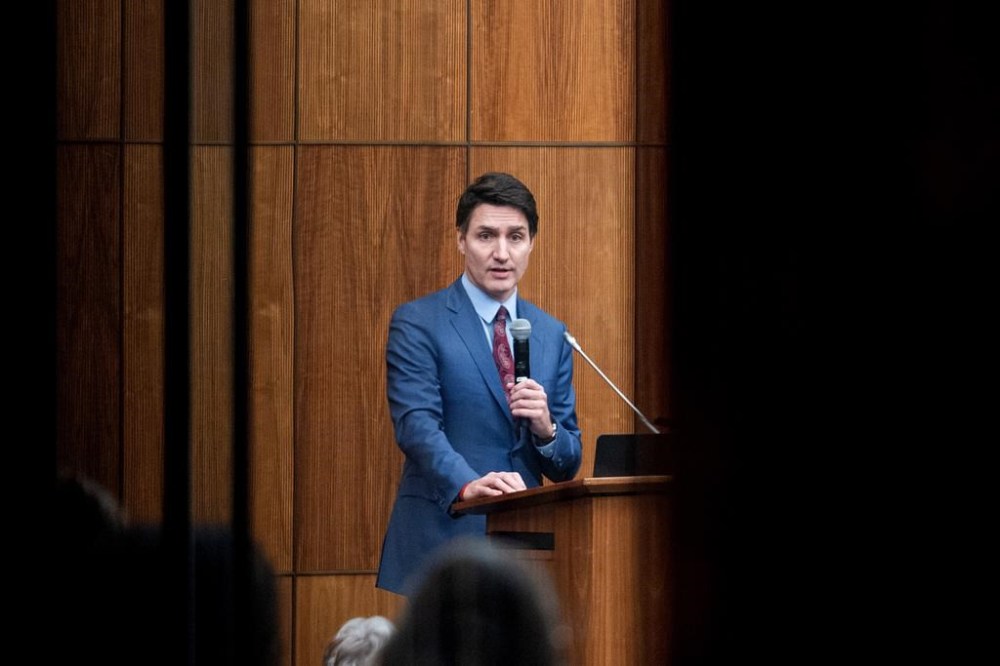 Prime Minister Justin Trudeau is pictured through glass as he speaks with members of his caucus in Ottawa, on Monday, Dec. 16, 2024. THE CANADIAN PRESS/Spencer Colby
