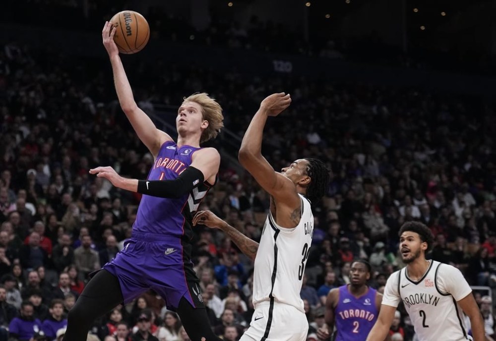 Toronto Raptors guard Gradey Dick (1) scores past Brooklyn Nets centre Nic Claxton (33) during first half NBA basketball action in Toronto on Thursday, December 19, 2024. THE CANADIAN PRESS/Nathan Denette