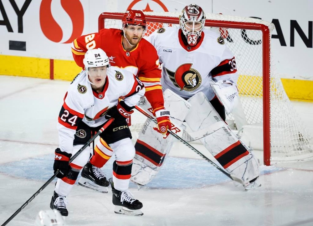 Ottawa Senators' Jacob Bernard-Docker, left front, and Calgary Flames' Blake Coleman, centre, watch the play with goalie Linus Ullmark during second period NHL hockey action in Calgary on Thursday, Dec. 19, 2024.THE CANADIAN PRESS/Jeff McIntosh