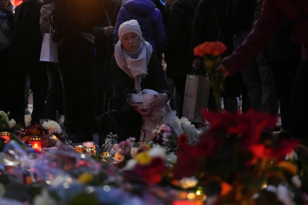 Citizens pay tribute for deaths outside St. John's Church near a Christmas Market, where a car drove into a crowd on Friday evening, in Magdeburg, Germany, Saturday, Dec. 21, 2024. (AP Photo/Ebrahim Noorozi)