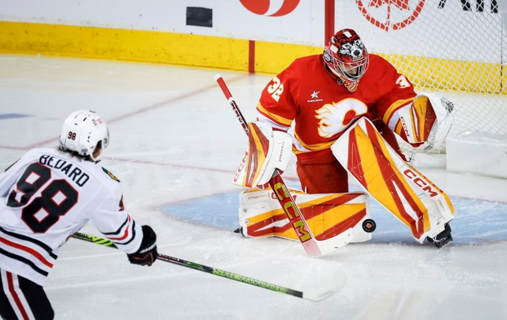 Chicago Blackhawks' Connor Bedard, left, has his shot stopped Calgary Flames goalie Dustin Wolf during first period NHL hockey action in Calgary, Alta., Saturday, Dec. 21, 2024. THE CANADIAN PRESS/Jeff McIntosh