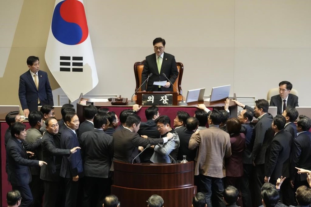 South Korea's National Assembly Speaker Woo Won Shik, top, speaks as lawmakers of the ruling People Power Party protest during a plenary session for the impeachment motion against the country's acting President Han Duck-soo at the National Assembly in Seoul, South Korea, Friday, Dec. 27, 2024. (AP Photo/Ahn Young-joon)