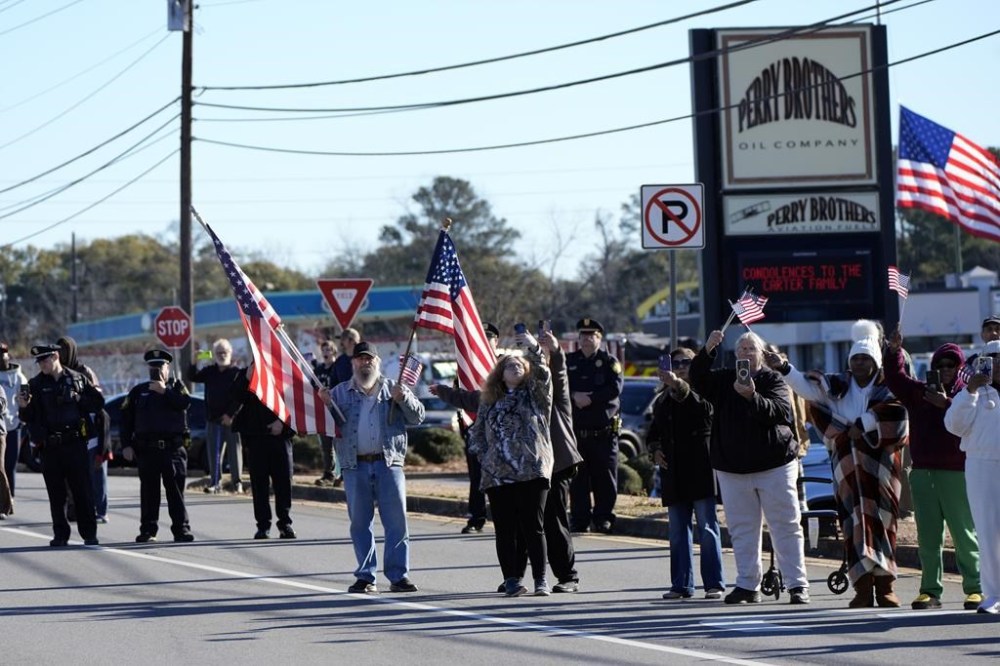 People line the road before the hearse with the casket of former President Jimmy Carter departs Phoebe Sumter Medical Center in Americus, Ga., Saturday, Jan. 4, 2025. Carter died Dec. 29 at the age of 100. (AP Photo/Alex Brandon, Pool)