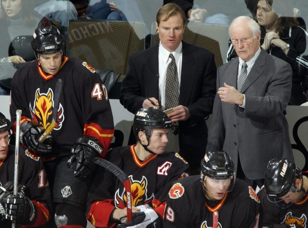 Calgary Flames center Scott Nichol, back left, climbs back on the bench as the team's new head coach Al MacNeilm back right, confers with his assistant Jamie Hislop, back center, in the first period of a game against the Colorado Avalanche in the Pepsi Center in Denver on Tuesday, Dec. 3, 2002. THE CANADIAN PRESS/AP-David Zalubowski